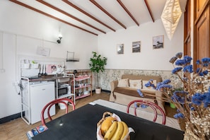 Een kleine keuken met een koelkast, magnetron en een eethoek met een tafel en stoelen.