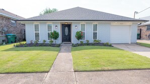 A single-story house with a dark front door, white brick exterior, and a garage.