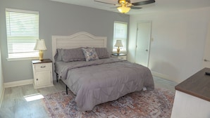 A bedroom with a bed, nightstands, a ceiling fan, and a patterned rug.