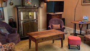 A cozy living room with a fireplace, vintage furniture, and a television. - Large family home in the country - sleeps 8 (Saint-Seine-sur-Vingeanne)