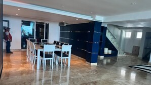 A spacious indoor area with a marble floor, a dining table with chairs, and a staircase.