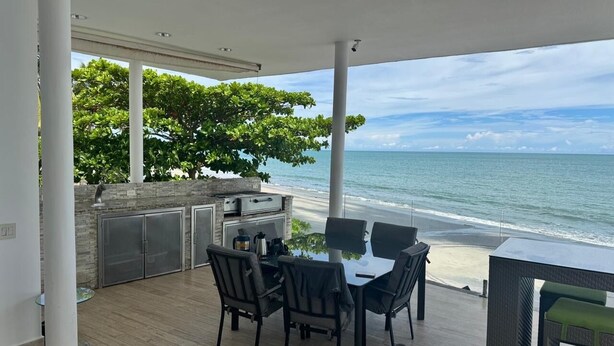 A covered outdoor dining area with a view of the beach and ocean.