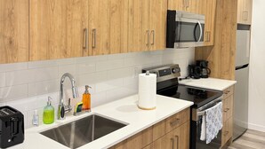 A modern kitchen with wooden cabinets, stainless steel appliances, and a white countertop.