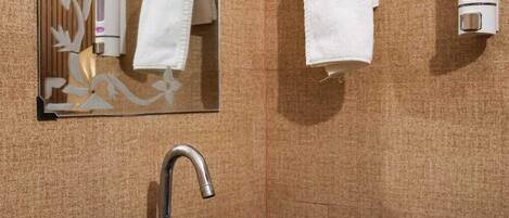 Un baño con un lavamanos negro, un espejo, dos anillas para toallas y un dispensador de jabón.