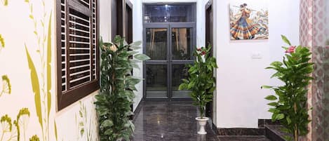 A hallway with potted plants, a door, and a wall-mounted artwork.