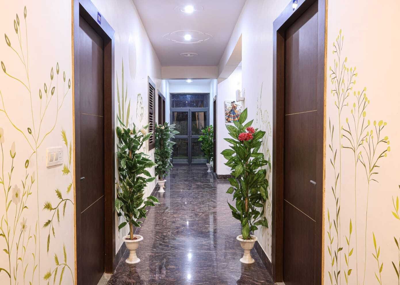 A hallway with marble flooring, potted plants, and doors on either side.