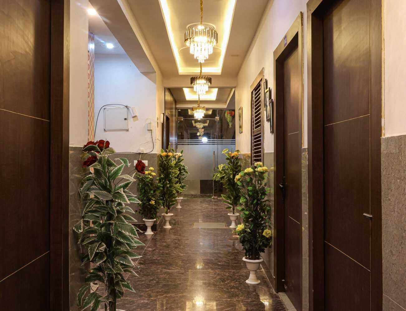 Un pasillo con plantas en macetas, un candelabro y una puerta al final.