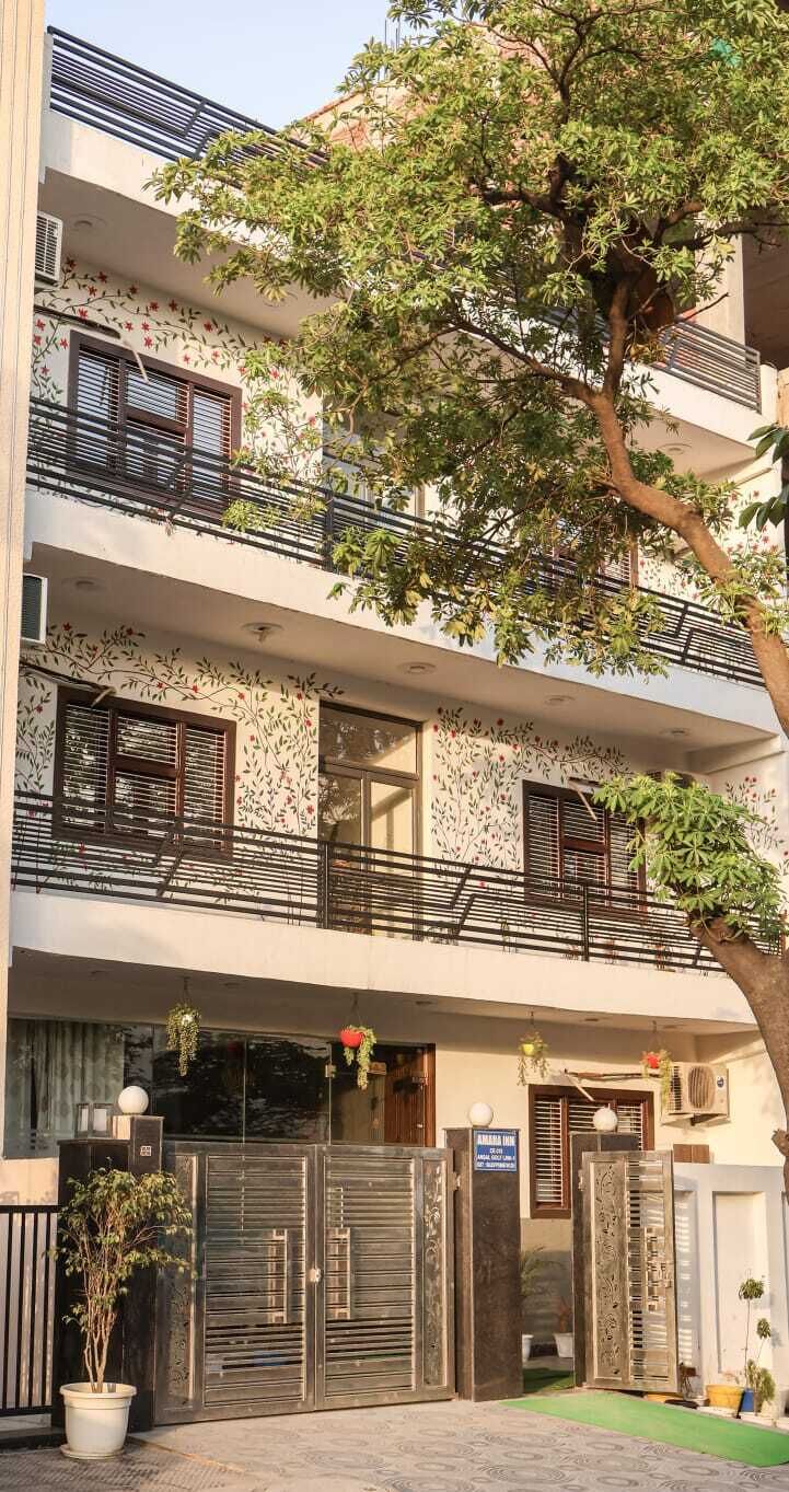 A multi-story building with balconies, a tree in front, and a gated entrance.