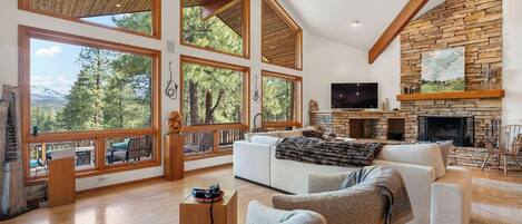 A spacious living room with large windows, a stone fireplace, and a cozy seating area.