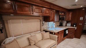 A compact living space with a sofa, kitchenette, and a ceiling with recessed lighting. - Colorado River RV in Enchanting Needles with beautiful views and boat launch. (Needles)