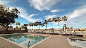 A swimming pool with lounge chairs and palm trees in the background. - Colorado River RV in Enchanting Needles with beautiful views and boat launch. (Needles)