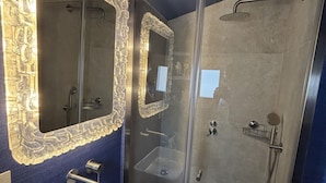 Een badkamer met een douche met glazen wand, een wastafel met spiegel en een decoratieve wand.