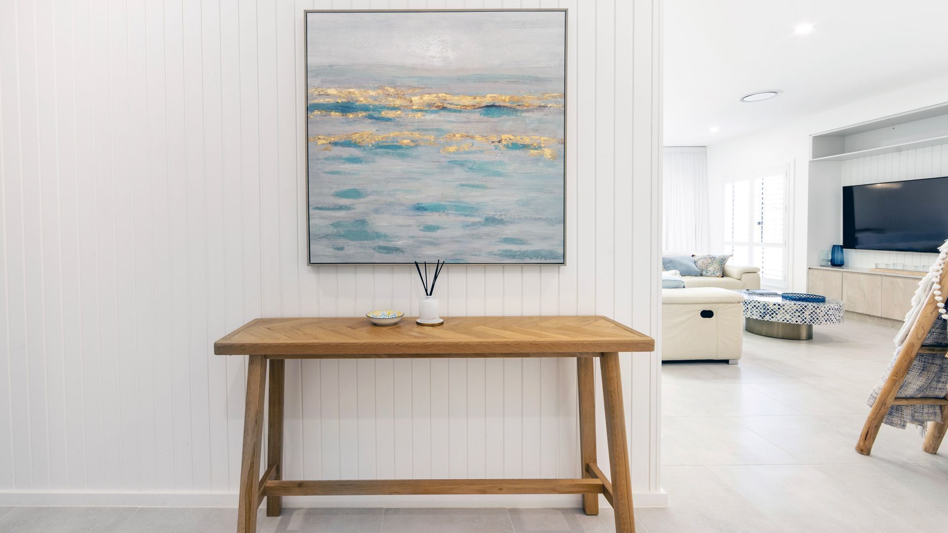 A modern living room with a wooden coffee table, a painting, and a sofa.
