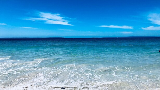 A beach with clear turquoise water and a clear sky.