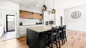 Moderni keittiö, jossa on keskeinen saareke, puukaapit ja riippuvalaisimet.