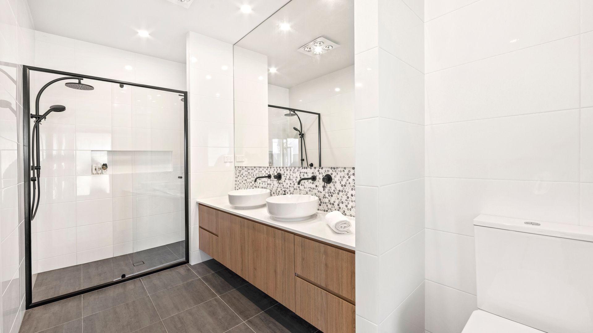 Ein modernes Badezimmer mit einer gläsernen Dusche, zwei Waschbecken und einer Marmor-Spritzschutzwand.