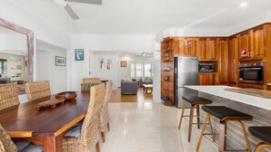 Una cucina moderna con mobili in legno, un frigorifero in acciaio inossidabile e un'area pranzo con sedie in vimini e un tavolo in legno.
