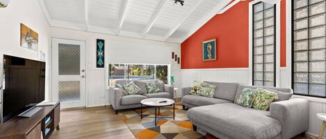 A living room with a grey sofa, a coffee table, and a TV on a wooden stand.