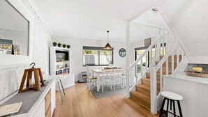 Una cocina amplia con zona de comedor, piso de madera y una escalera que sube a otro nivel.