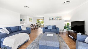 A modern living room with two sofas, a coffee table, and a TV. - Sandy Adventures - Pet Friendly - 1 Min to Beach (Callala Beach)