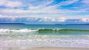A beach with waves, a clear sky, and distant land. - Sandy Adventures - Pet Friendly - 1 Min to Beach (Callala Beach)