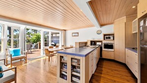 Een moderne keuken met houten kastjes, een centraal eiland en een eethoek met uitzicht op de omgeving.
