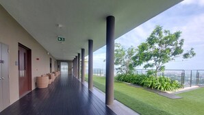 Un pasillo con vista a un césped verde y árboles, que conduce a una puerta a la izquierda.