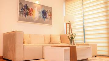 A living room with a beige sofa, a white coffee table, and a painting on the wall.