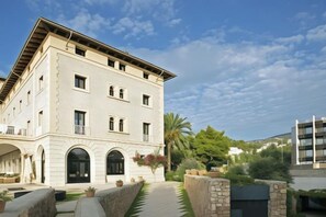 A multi-story building with a symmetrical facade, arched windows, and a central entrance. - Hotel Hospes Maricel & Spa (Ca's Catala)