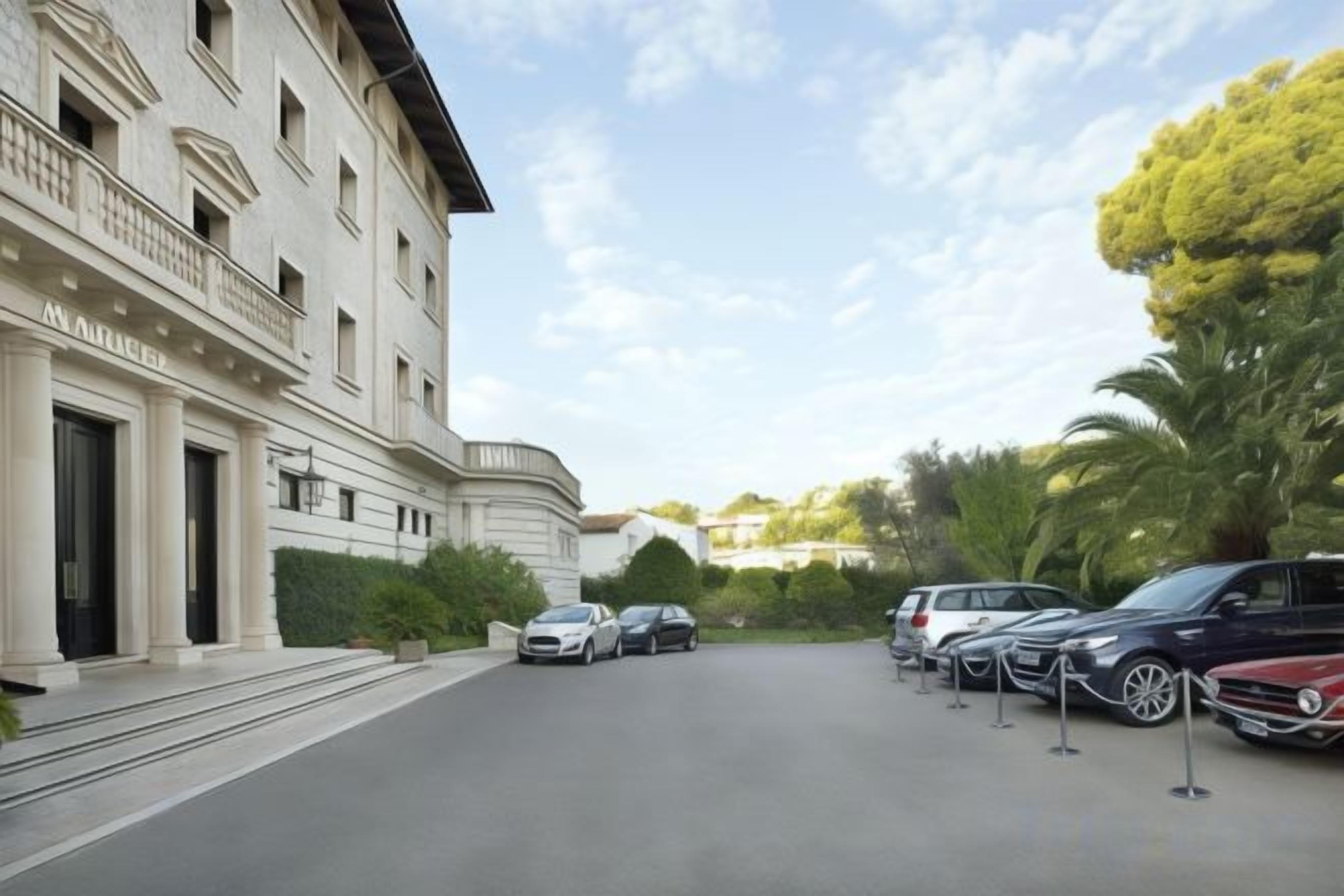 Un edificio con facciata classica, un'area di parcheggio con diverse auto e cielo sereno.