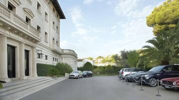 Un edificio con facciata classica, un'area di parcheggio con diverse auto e cielo sereno.