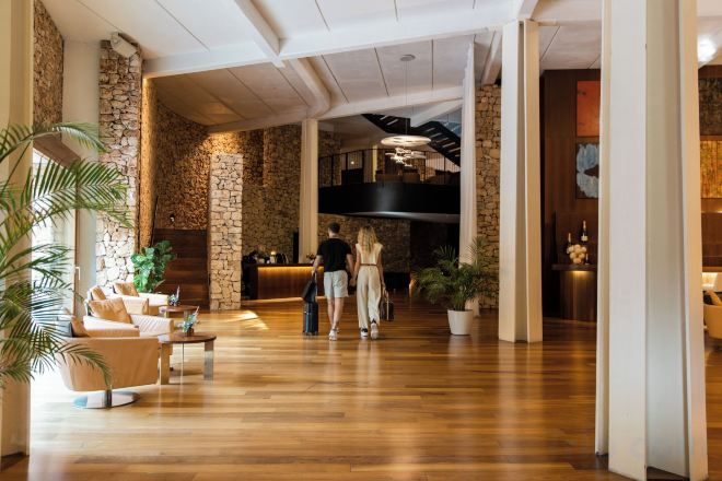 Un vestíbulo con mostrador de recepción, zona de estar y una escalera que lleva a un nivel superior.