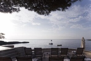 A seaside terrace with outdoor seating and a view of the sea. - Hotel Hospes Maricel & Spa (Ca's Catala)