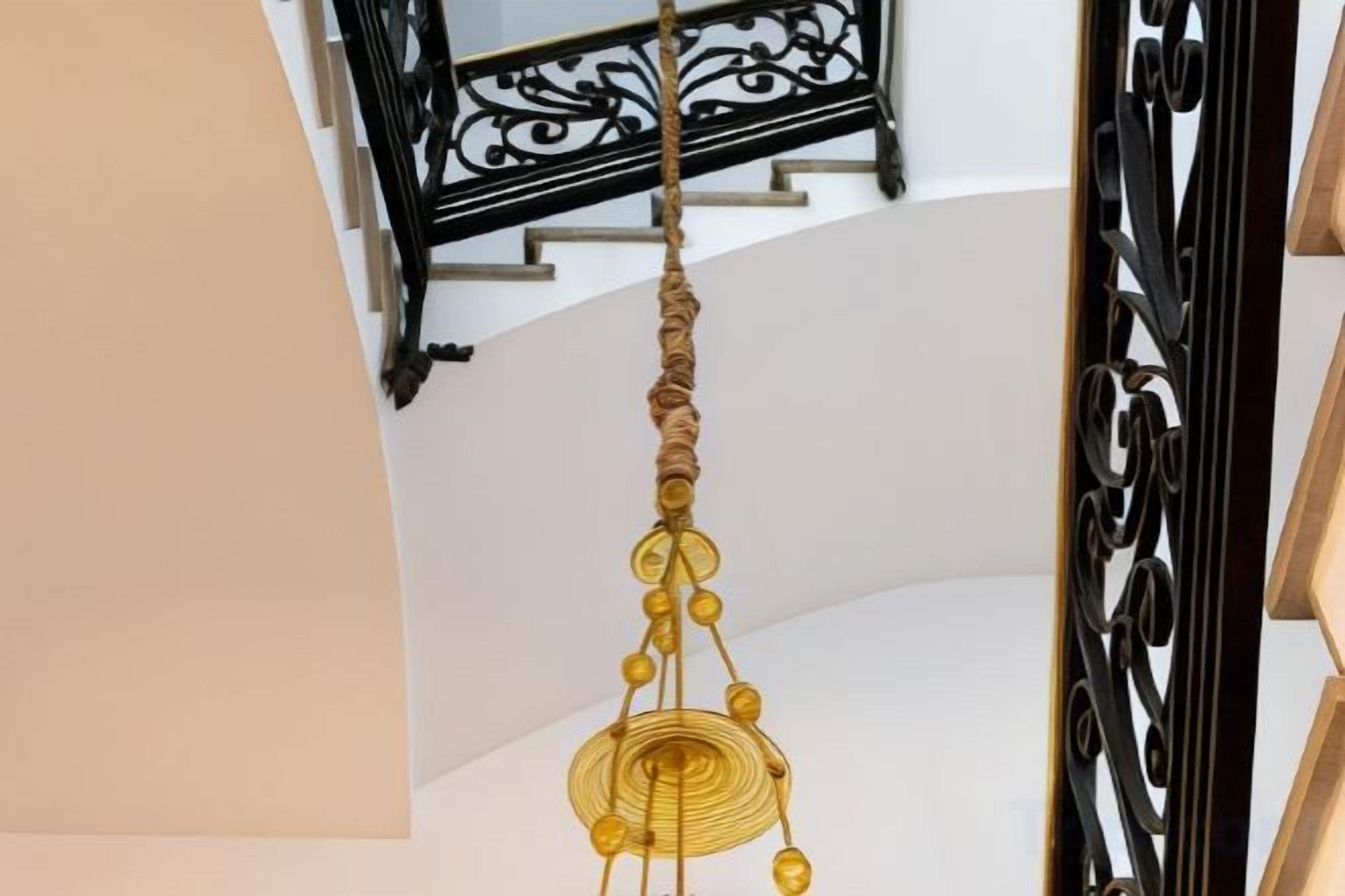 Una escalera con barandilla decorativa y una lámpara colgante.