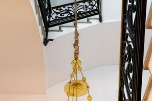 A staircase with a decorative railing and a hanging light fixture. - Hotel Hospes Maricel & Spa (Ca's Catala)