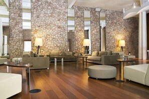A modern hotel lobby with stone walls, multiple seating areas, and ambient lighting. - Hotel Hospes Maricel & Spa (Ca's Catala)