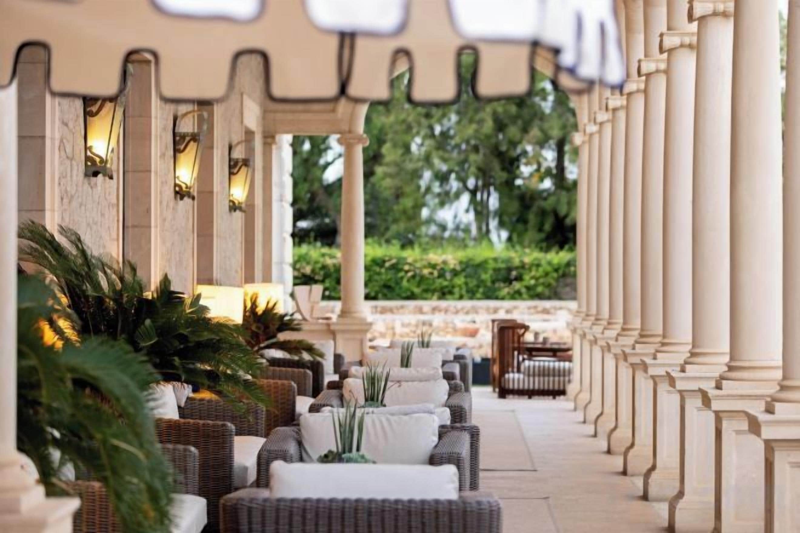 A covered outdoor seating area with wicker furniture and columns.
