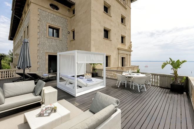 Un balcón con cama, sofá, mesa y silla.
