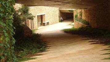Un pasillo interior con piso de concreto, paredes de piedra y una persona caminando.