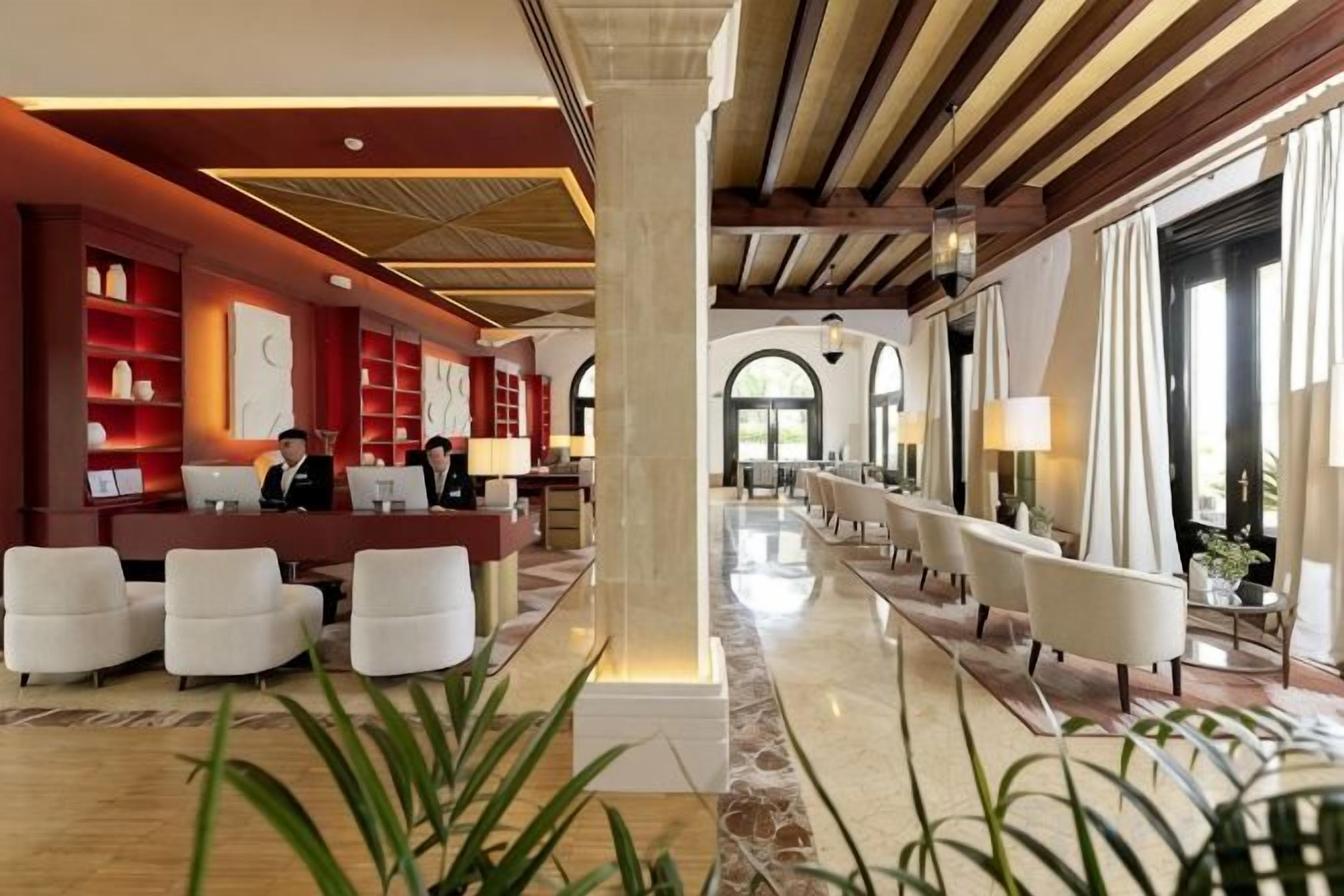 Un hall de hotel con mostrador de recepción, zona de estar y amplias ventanas.
