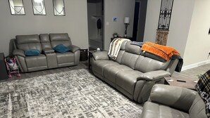 A living room with two leather sofas, a patterned rug, and a staircase in the background.