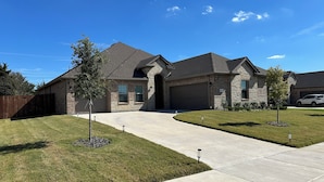 A two-story house with a stone facade, a garage, and a well-maintained lawn.