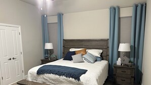 A neatly arranged bedroom with a bed, bedside tables, and a nightstand.