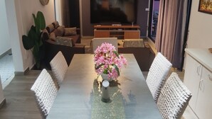 A modern living room with a flat-screen TV, a sofa set, a dining table with chairs, and a potted plant. - Villa atomium ile maurice souillac 127m2 100m to the beach (Souillac)