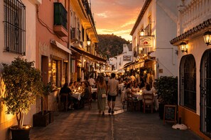A narrow street lined with restaurants and cafes, with people dining and walking. - El Fogón: Exclusive designer loft in the heart of Benahavís (Benahavís)