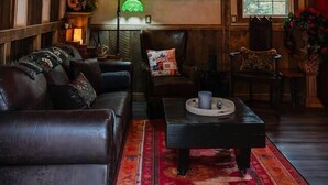 A cozy room with a wooden ceiling, a chandelier, a fireplace, and a sofa. - The Wizard's Retreat near Top Attractions! (Sevierville)