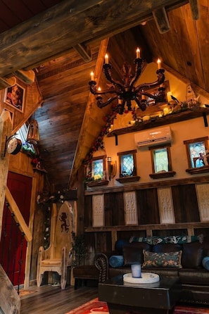 A rustic interior with wooden beams, a chandelier, a fireplace, and a cozy seating area.