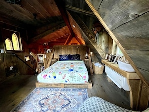 Une chambre à coucher rustique en bois, avec un lit en mezzanine, une petite table de chevet et une fenêtre donnant sur un paysage agréable.