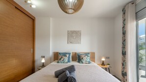 A hotel room with a large bed, two bedside tables with lamps, a decorative wall piece, and a sliding door.