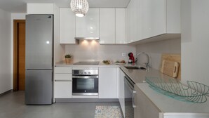 A modern kitchen with a stainless steel refrigerator, built-in oven, and a pendant light.